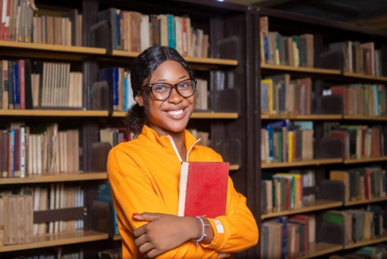 Cheerful researcher near a bookshelf